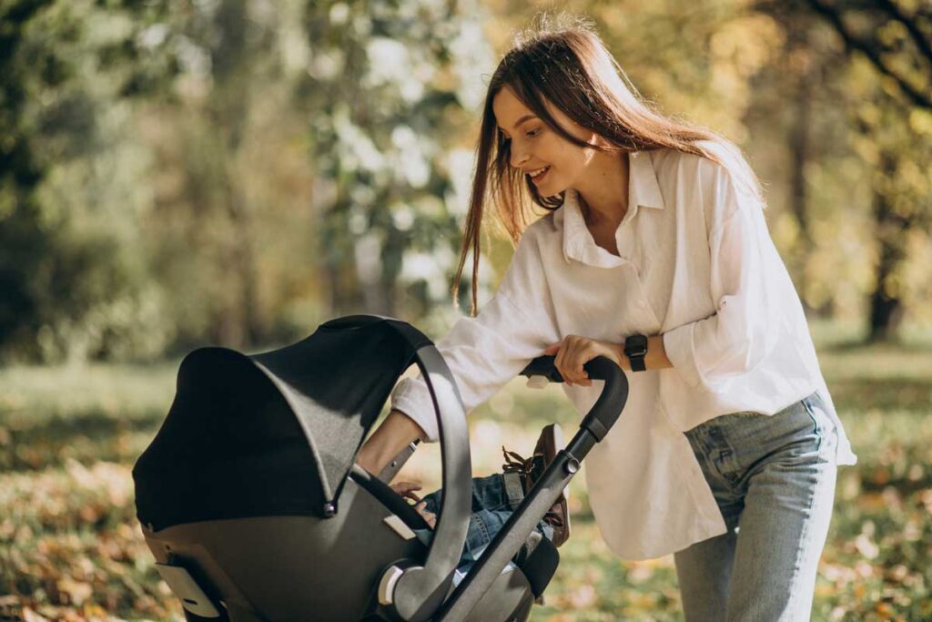 A young mom pushing a baby stroller.