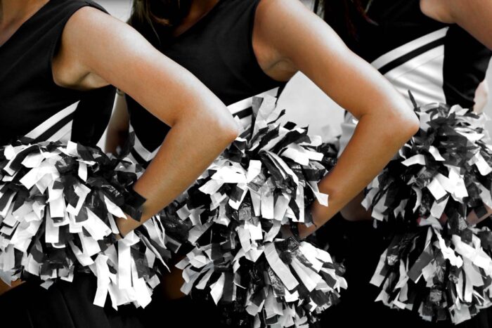 Close up of Cheerleaders in Uniform Holding Pom-Poms - cheerleading sex abuse