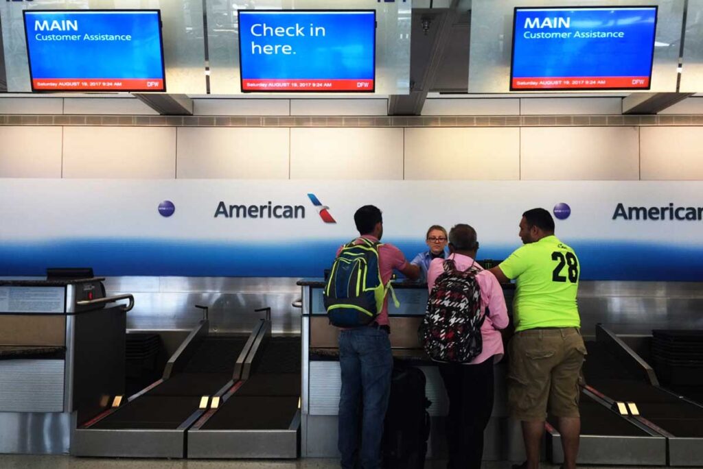 Airlines passengers at an American Airlines customer service counter, representing the American Airlines bag fees class action lawsuit settlement.