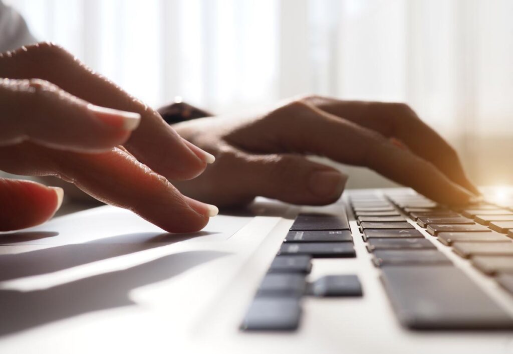 Close up of a womans hands using a laptop computer.