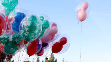 Colorful Disney shaped balloons against a blue sky.