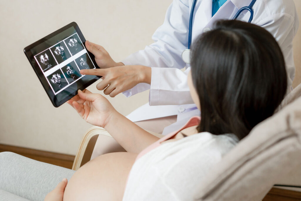 A doctor showing an expected mother an ultrasound on a tablet, representing the Fertility Centers of Illinois data breach class action settlement.