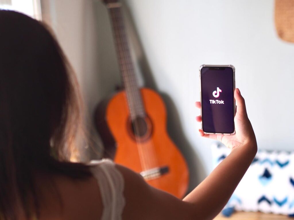 Young woman using her smartphone to record a TikTok video.