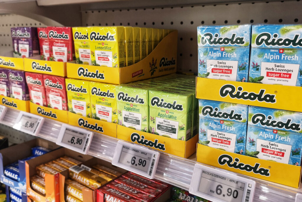 Close up of Ricola boxes for sale on a grocery store shelf.