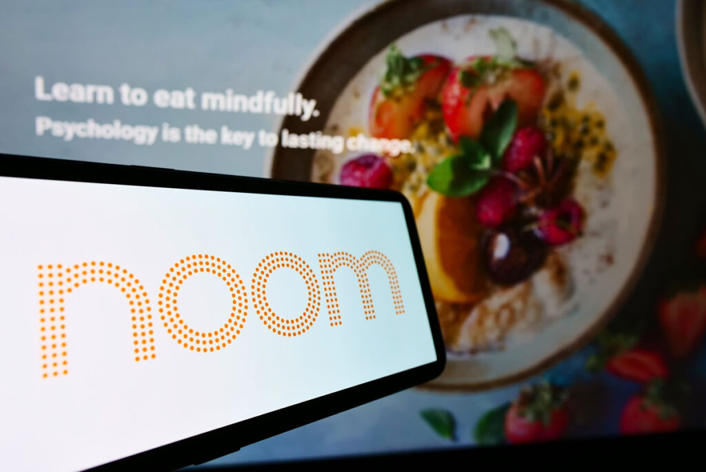Smartphone with logo of US weight-loss platform company Noom Inc on screen.