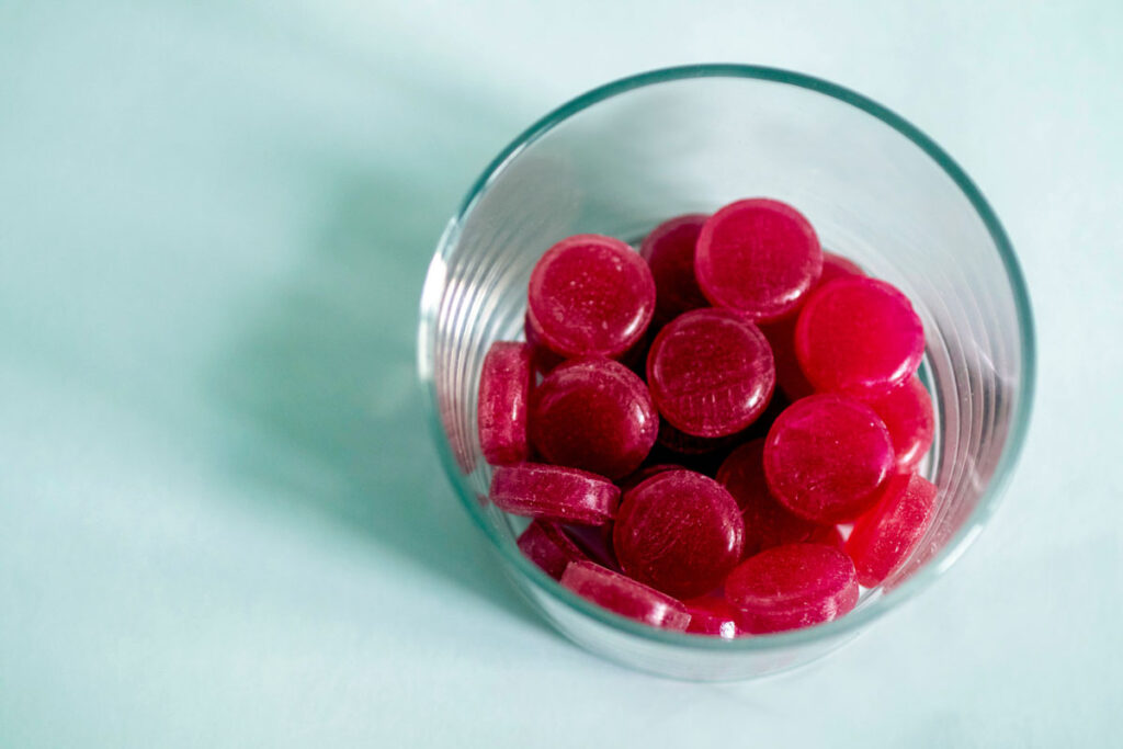 Close up of red lozenges in a glass cup.