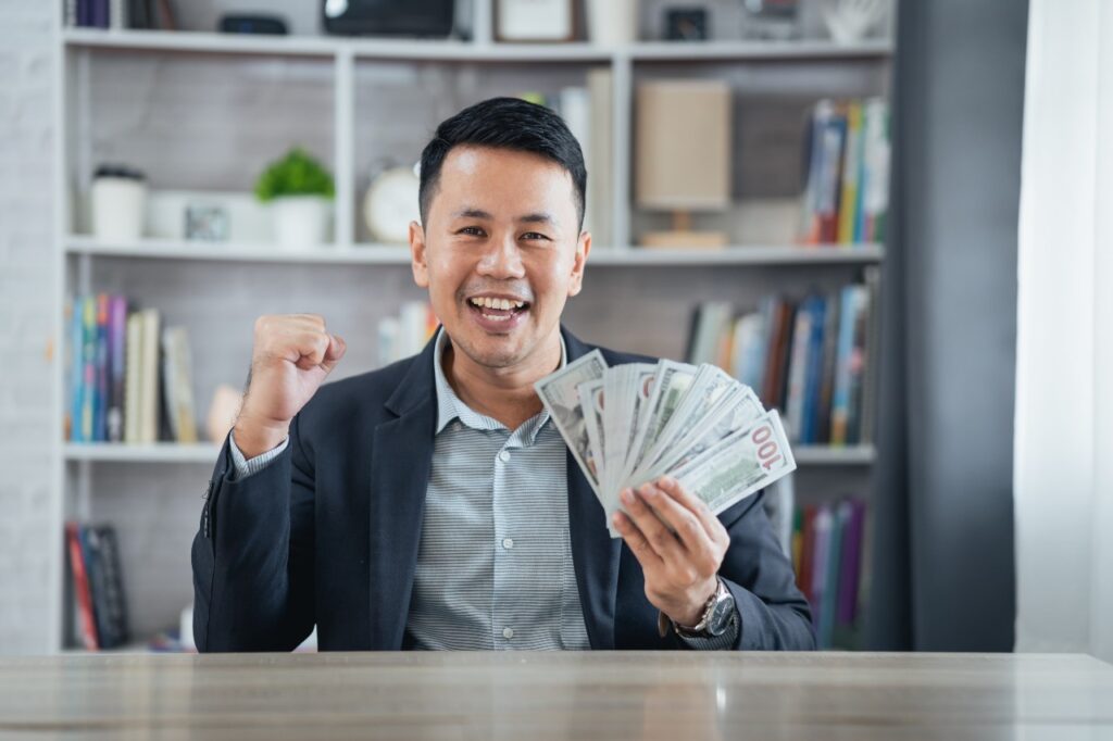 Happy Man with money in hand. Checks are on the way in a number of class action settlements.