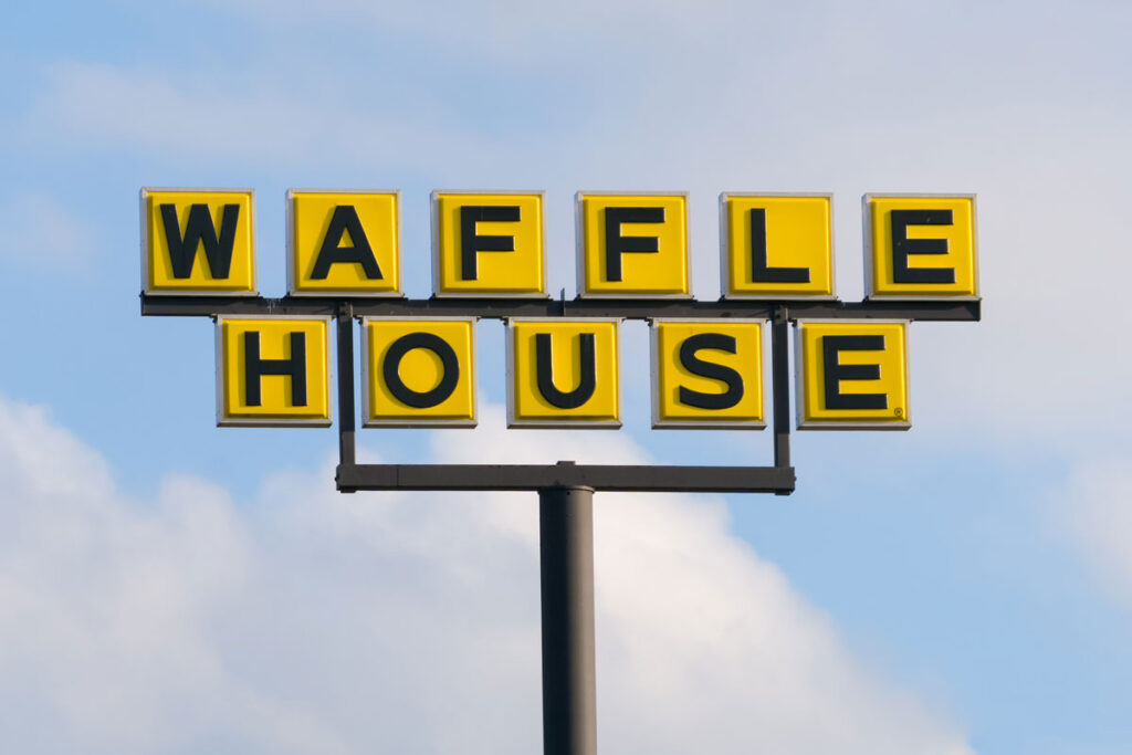 Waffle House signage against a blue sky.