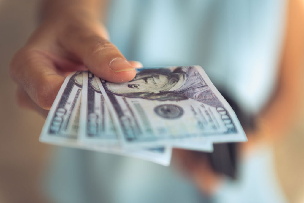 Close up of a females hands holding cash.