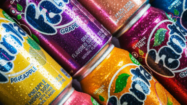 Close up of Fanta cans in various flavors covered in water droplets.