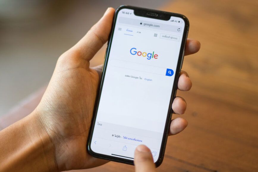 Close up of hands holding a smartphone with Google logo displayed.