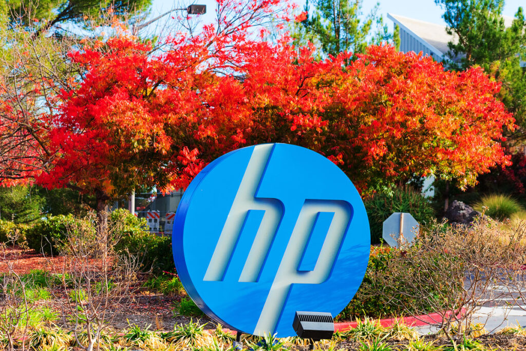 Blue, white round HP logo of Hewlett-Packard Company in front of foilage, representing the HP equal pay class action lawsuit settlement.