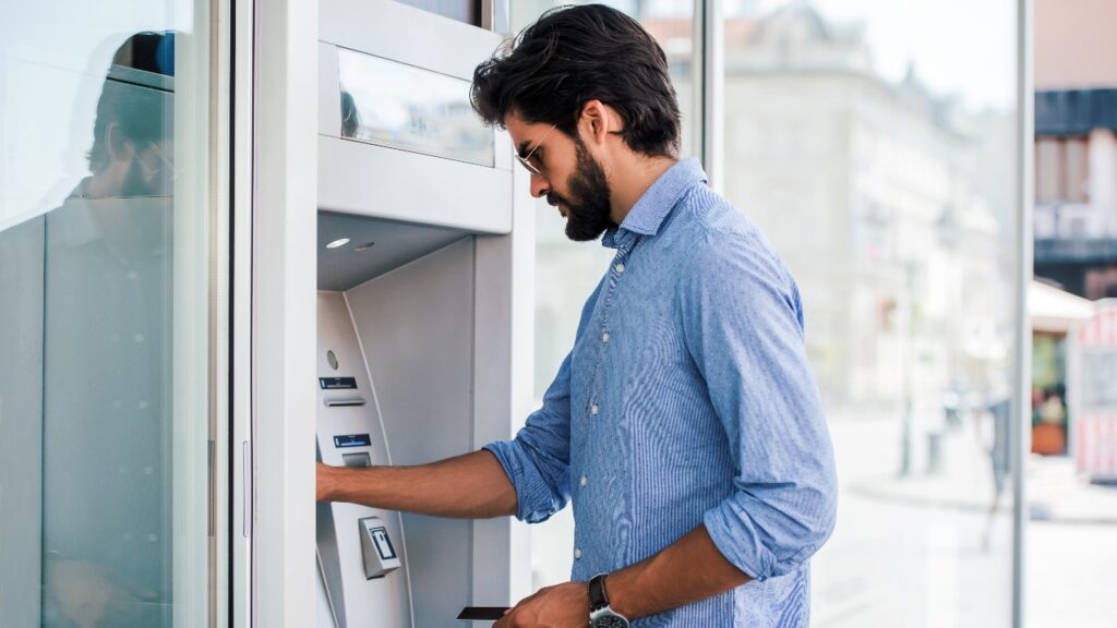 Man depositing money at automatic teller machine