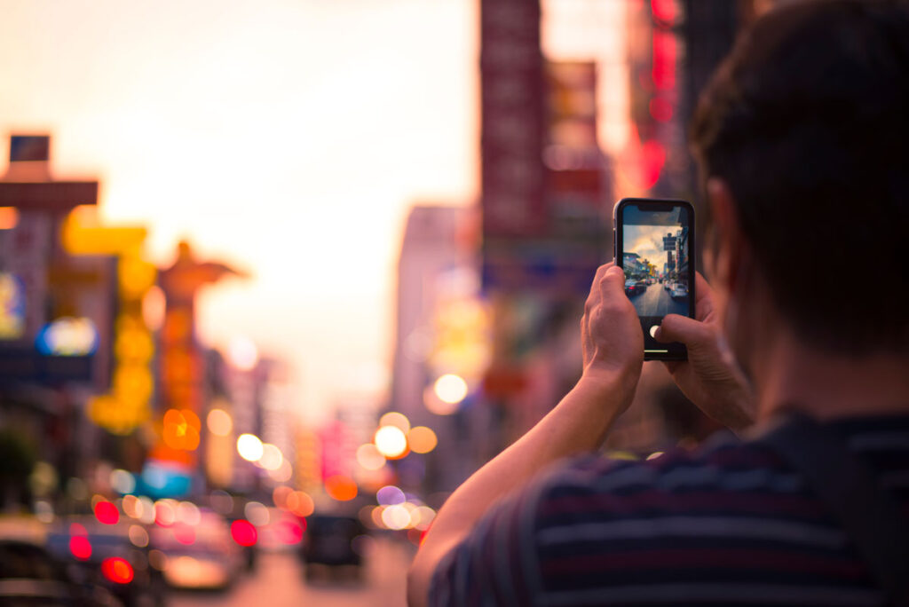 Back view of a man taking a photo of a city during sunset hour, representing the AI image generators class action lawsuit.