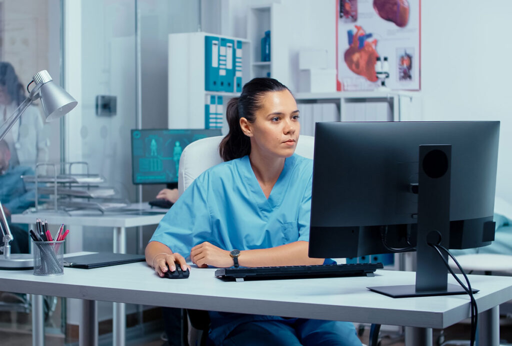 A nurse working on a computer at a nursing station, representing the Menorah Medical Center class action lawsuit settlement.