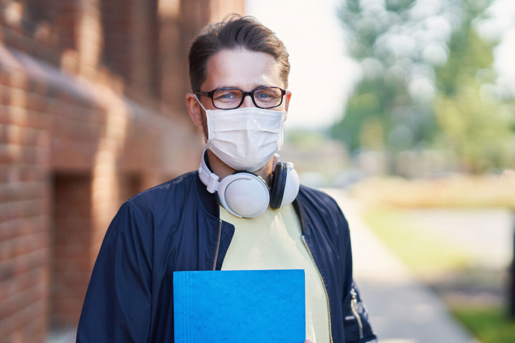 Male university student wearing a mask during the COVID-19 pandemic, representing the Quinnipiac University tuition class action lawsuit settlement.