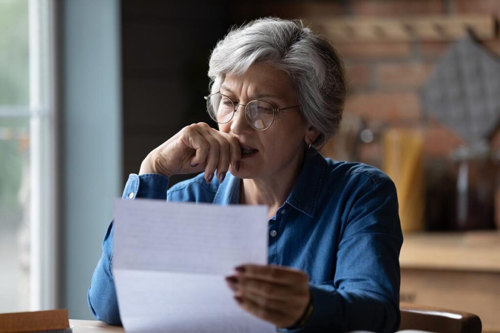 Elderly woman reading a letter with suspicion - Transworld debt collection
