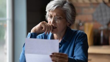 Elderly woman reading a letter with suspicion.