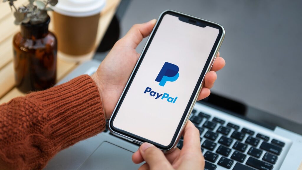 Hands on phone logging into PayPal - PayPal data breach