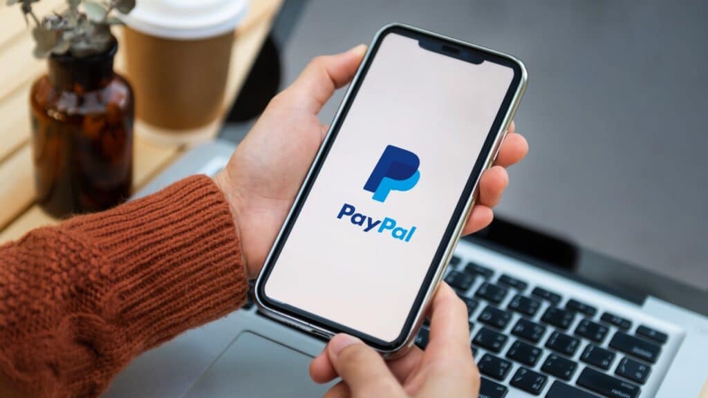 Manos en el teléfono iniciando sesión en PayPal: violación de datos de PayPal