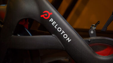 Peloton logo on the base of flagship stationary exercise bike setup for fitness riding use.