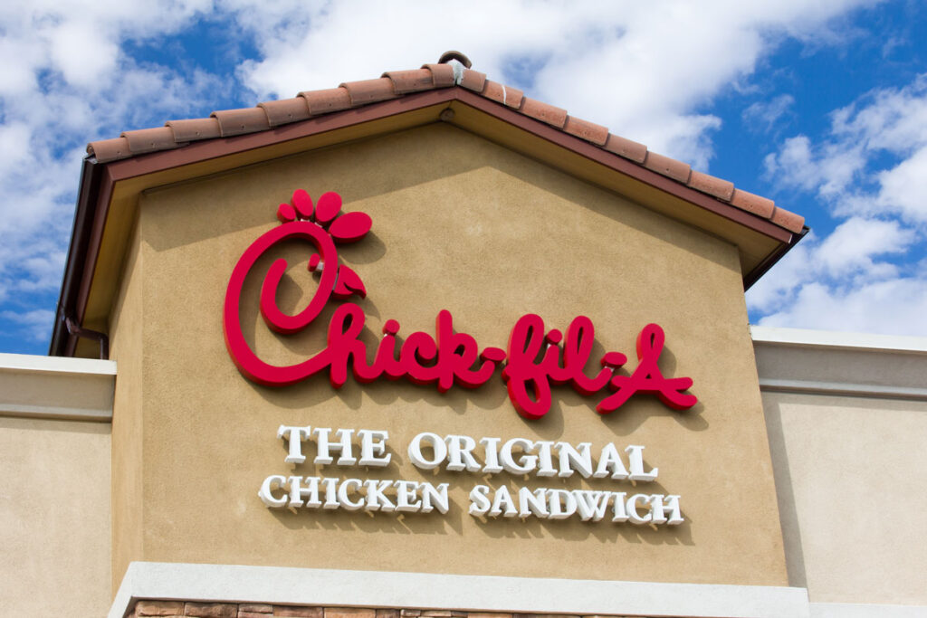 Close up of Chick-fil-a signage against a bright blue sky.