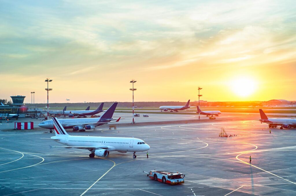 View of airplanes at an airport during sunset hour.