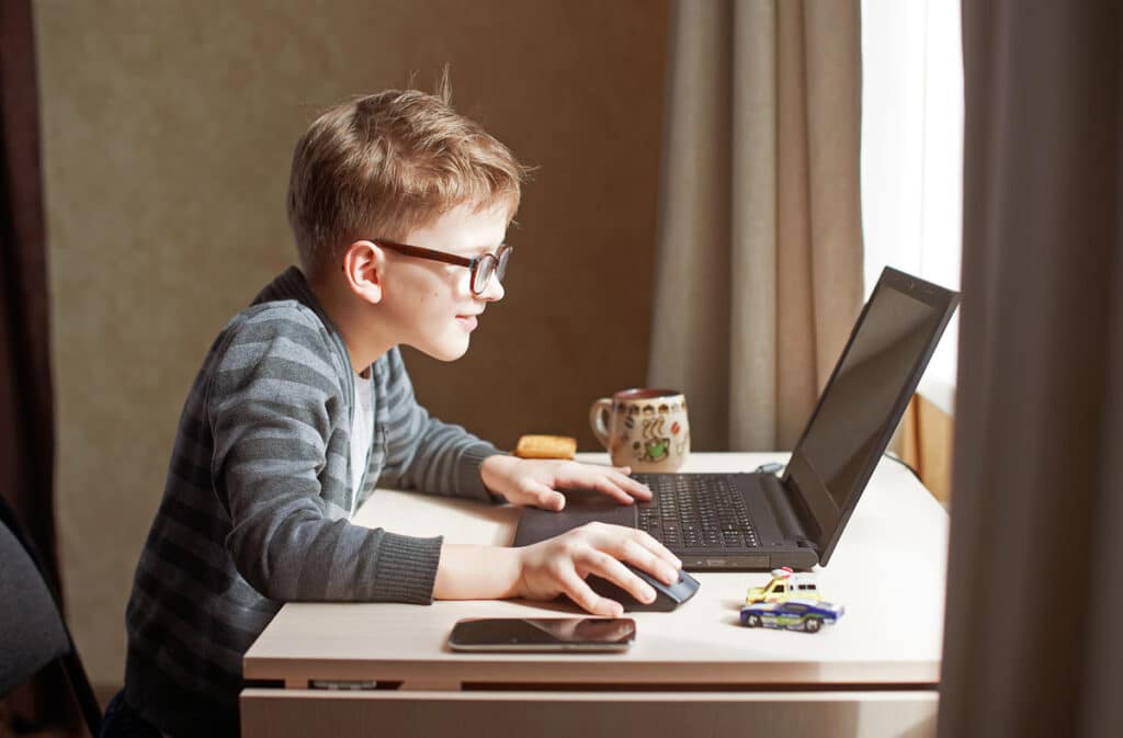 Close up of a young boy playing a game on his computer.