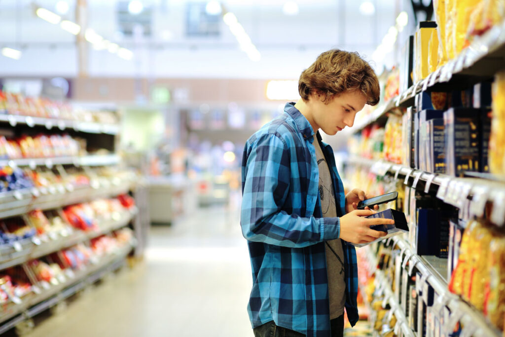 Young man reading product information inside a grocery store.