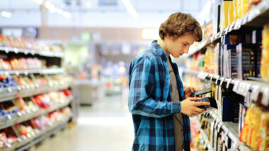 Young man reading product information inside a grocery store.