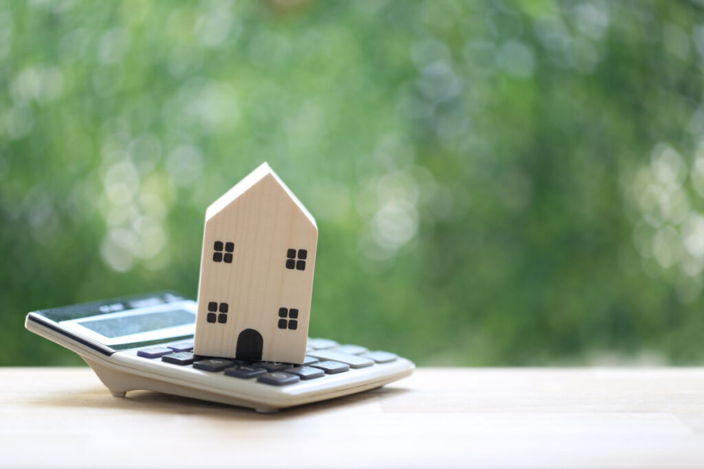 Small wooden toy house sitting on calculator