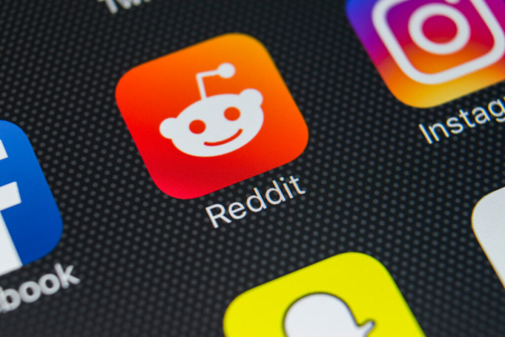 Reddit application icon on Apple iPhone X smartphone screen close-up.