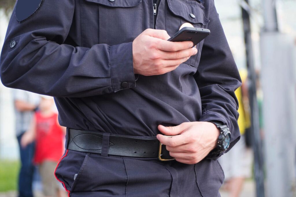 Mid shot of a police officer in uniform using his smartphone.