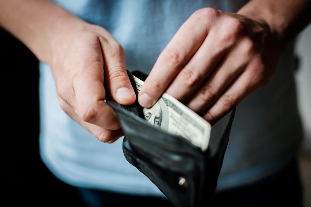 Close up of a man pulling cash out of his wallet.