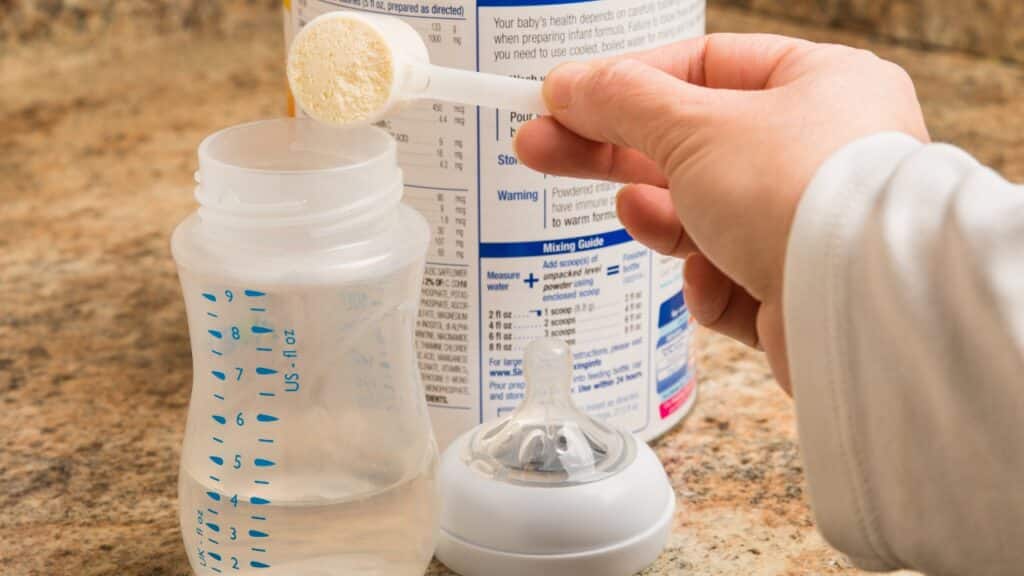 Mother prepares baby formula in kitchen