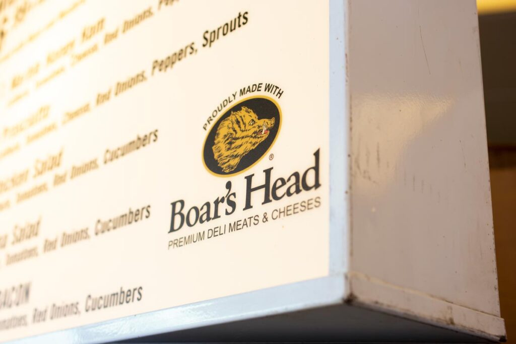 A view of the Boar's Head logo on the corner of a restaurant menu sign.