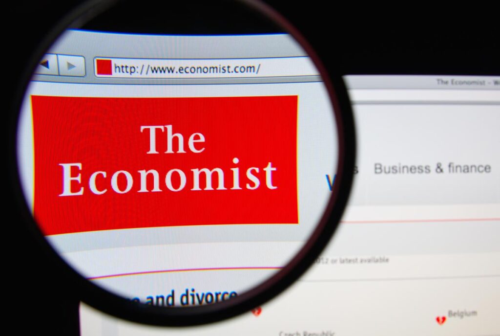 Photo of The Economist homepage on a monitor screen through a magnifying glass, representing the Economist Michigan class action settlement.