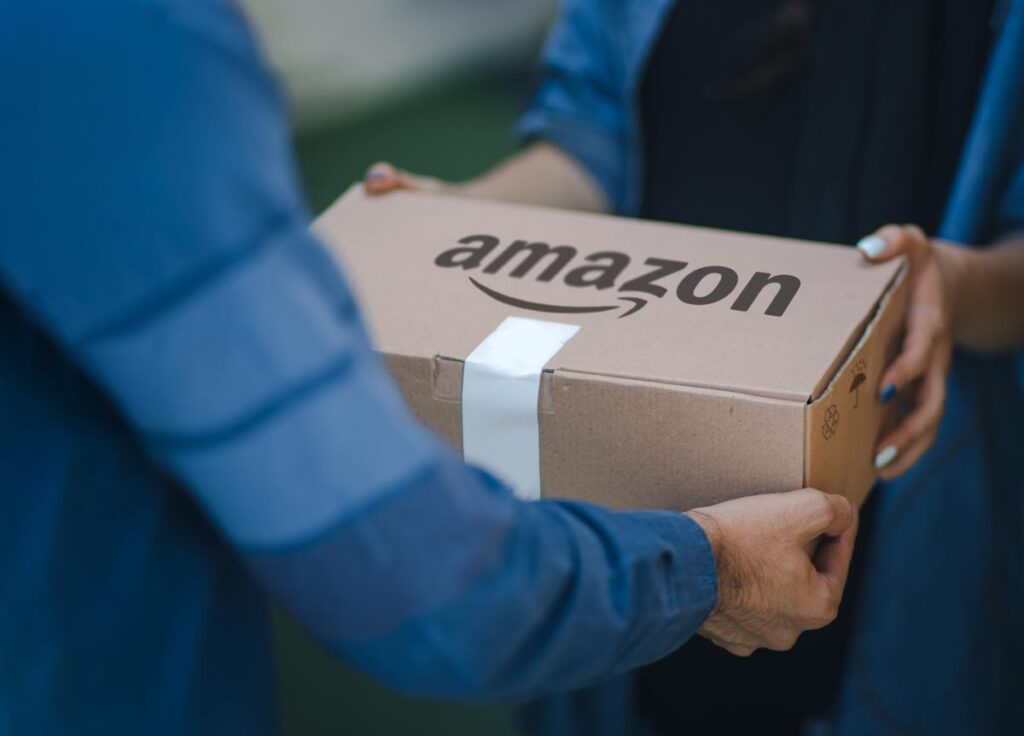Selective focus on man delivering parcel with amazon logo on cardboard.