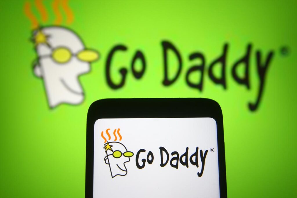 GoDaddy Inc. logo is seen on a mobile phone and a computer screen, representing the GoDaddy data breach.