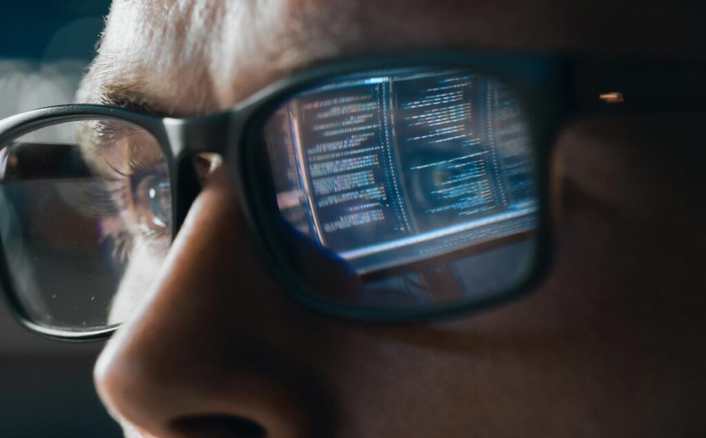 Close-up Portrait of Software Engineer Working on Computer, Line of Code Reflecting in Glasses, representing a biometric information ruling in Illinois.