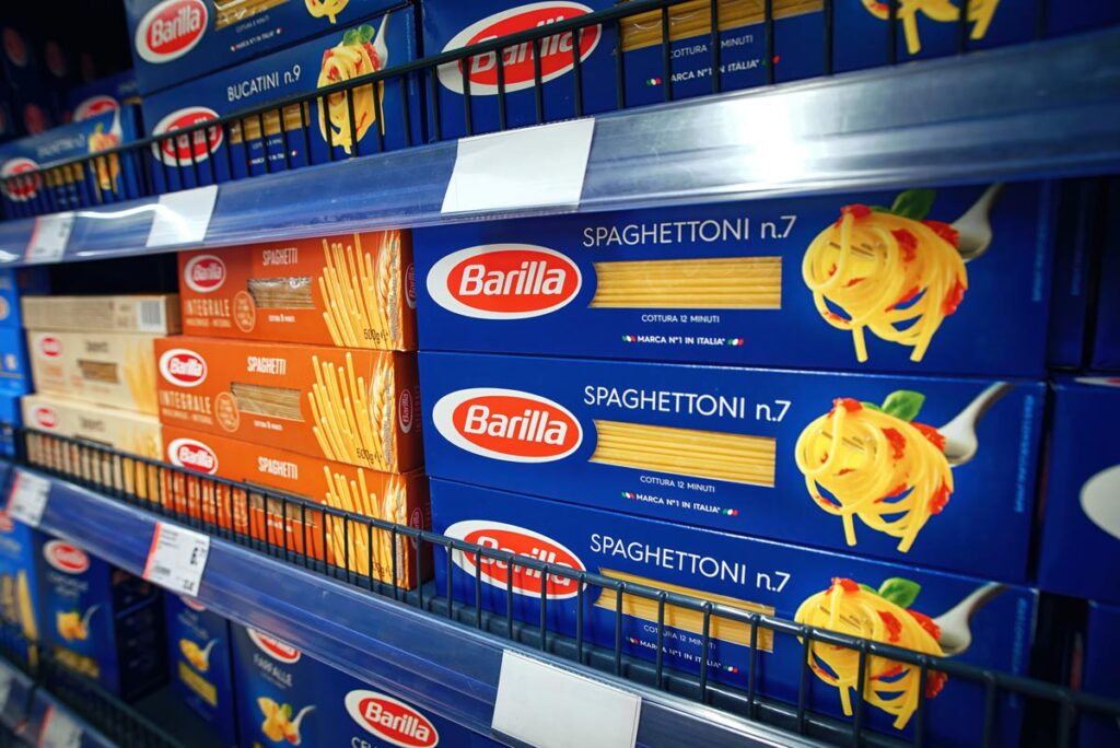 Barattoli di pasta Barilla in vendita su uno scaffale di generi alimentari.