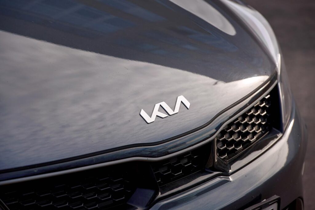 KIA Motors new angular logo on hood of dark grey Kia vehicle.