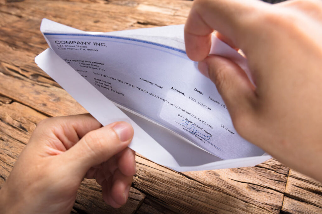 Cropped hands of businessman opening envelope with paycheck.