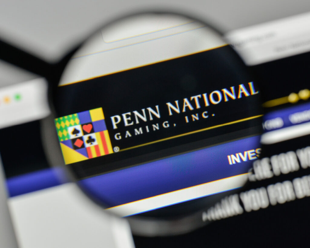 Magnifying glass looking at Penn National Gaming Inc. website representing the Missouri gaming tip pooling settlement.