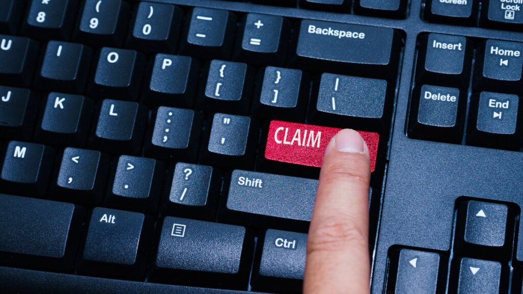 A person presses a red "claim" button on a black computer keyboard, representing settlements closing soon.