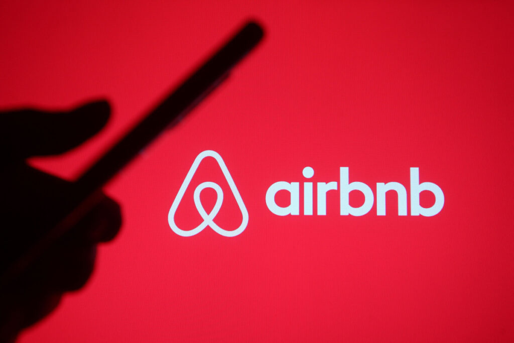 airbnb logo with a shadow of a person holding a cell phone