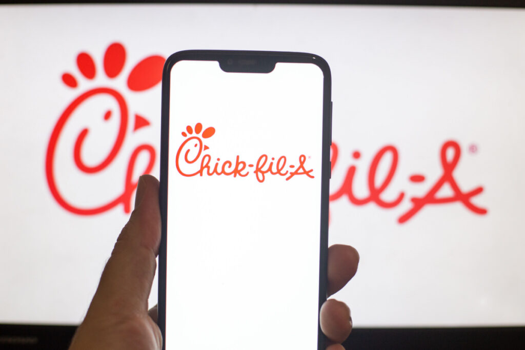 A person holds a cellphone with Chick-Fil-A logo on it, representing the Chick-fil-A data breach