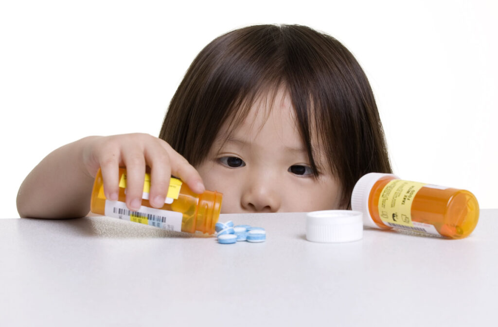 Young chiid playing with prescription pills