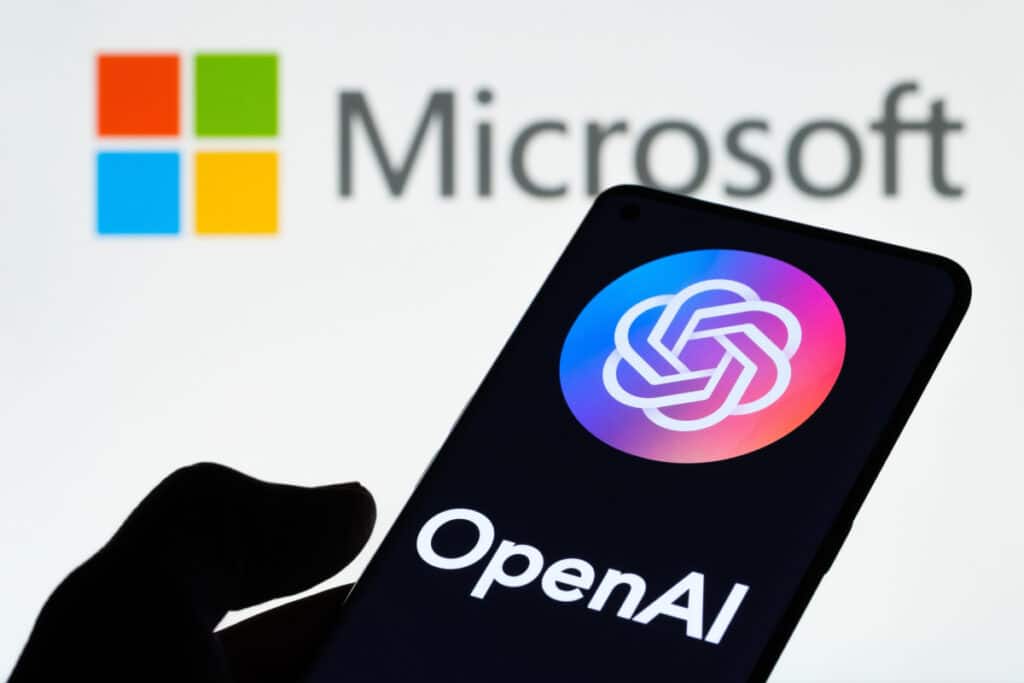 Open AI logo on cellphone with Microsoft logo in background