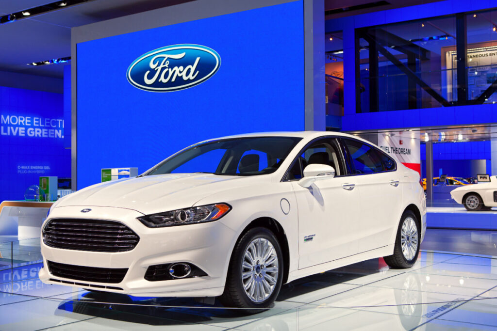 Ford Fusion on showroom with Ford Logo behind the car